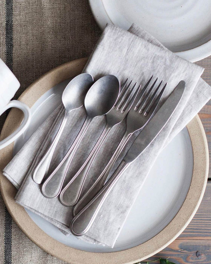 Coventry Stainless Steel Flatware — cutlery arranged on a folded napkin; Farmhouse Pottery
