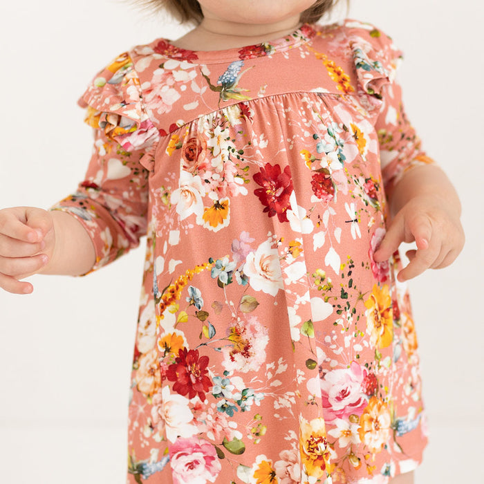 Orange, white and red floral dress close on toddler.