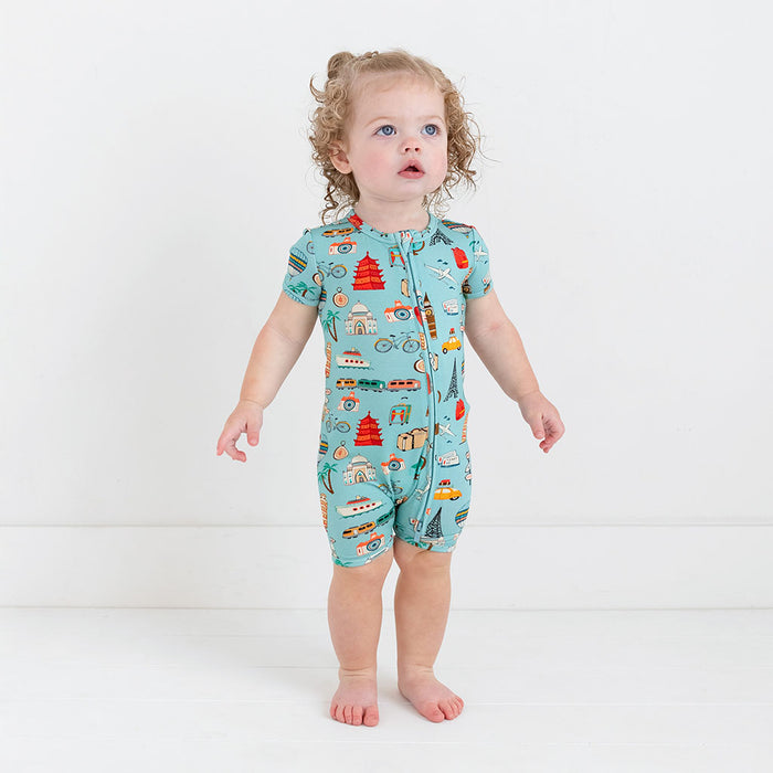 Girl wearing Short Sleeve short length zippered romper in aqua with iconic structures, buildings, and modes of transportation printed all over
