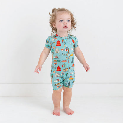 Girl wearing Short Sleeve short length zippered romper in aqua with iconic structures, buildings, and modes of transportation printed all over